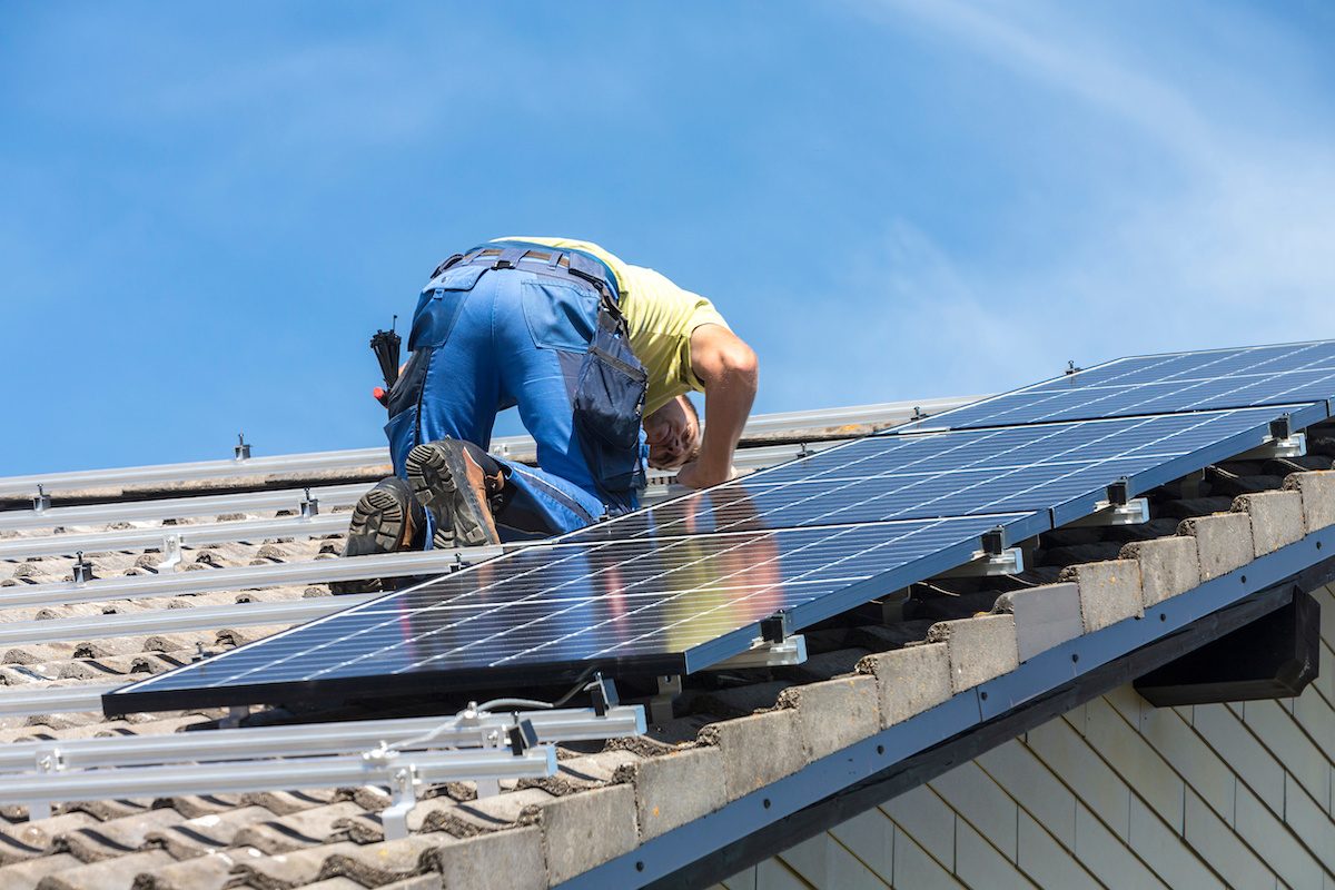 Installing solar photovoltaic panel system. Solar panel technician installing solar panels on roof. Alternative energy ecological concept.