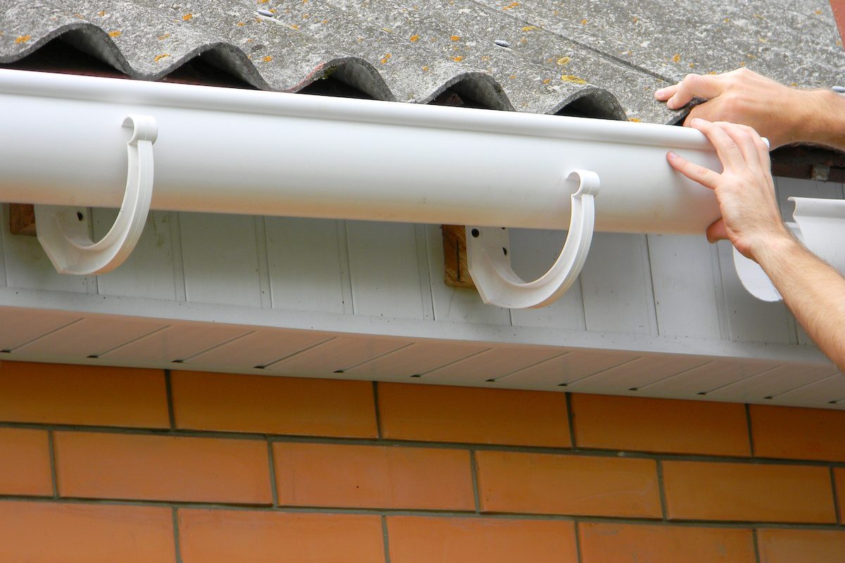 Contractor installing plastic roof gutter. Plastic Guttering, Rain Guttering & Drainage by Handyman hands.